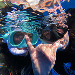 Two snorkelers underwater with bubbles and clear blue water.