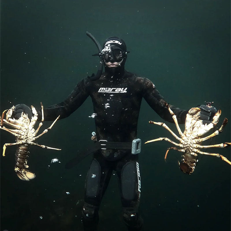 Vance in a wetsuit holding two lobsters underwater